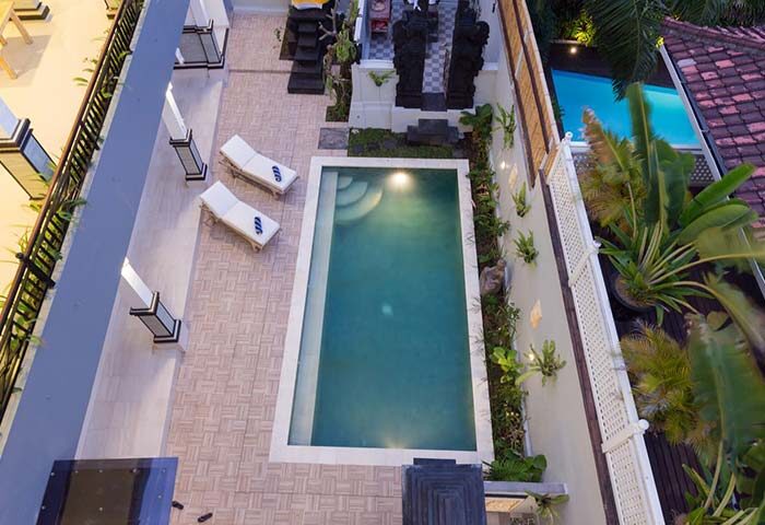 Amerta Seminyak gay-friendly hotel aerial view. Pool, lounge chairs, and Balinese statues. A perfect gay travel destination in Seminyak.
