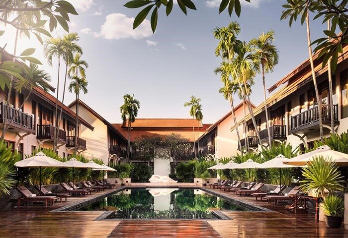 Anantara Angkor Resort pool view. Gay-friendly hotel with palm trees, sun loungers, and lush greenery. Perfect for gay men's travel.