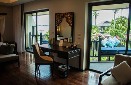 Anantara Bophut Koh Samui Resort room interior. Desk with mirror, chair, and balcony with daybed. Gay-friendly hotel stay in Thailand.