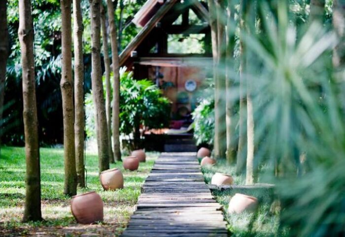 Path to a bungalow at Anantara Bophut Koh Samui Resort. Gay-friendly hotel with lush greenery & clay pots lining the walkway.