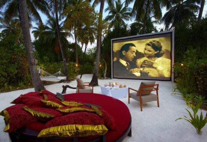Gay-Friendly Anantara Kihavah Maldives Villas: Outdoor cinema with daybed, chairs, and table. A romantic getaway for gay men's travel.