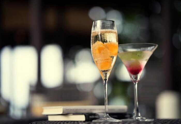 Cocktails at Anantara Lawana Koh Samui Resort, a gay-friendly hotel. Champagne flute with orange slices, martini glass, and books.