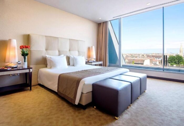 Anantara New York Palace, Budapest bedroom. Gay-friendly, pet-friendly hotel room with a large window overlooking the city.