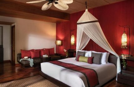 Gay-Friendly Hotel Anantara Rasananda Koh Phangan Villas: A luxurious villa bedroom with a canopy bed, red accents, and stylish decor.