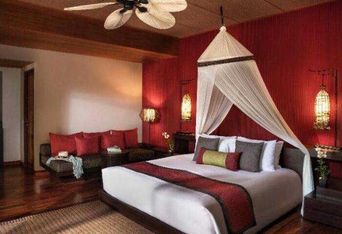 Gay-Friendly Hotel Anantara Rasananda Koh Phangan Villas: A luxurious villa bedroom with a canopy bed, red accents, and stylish decor.