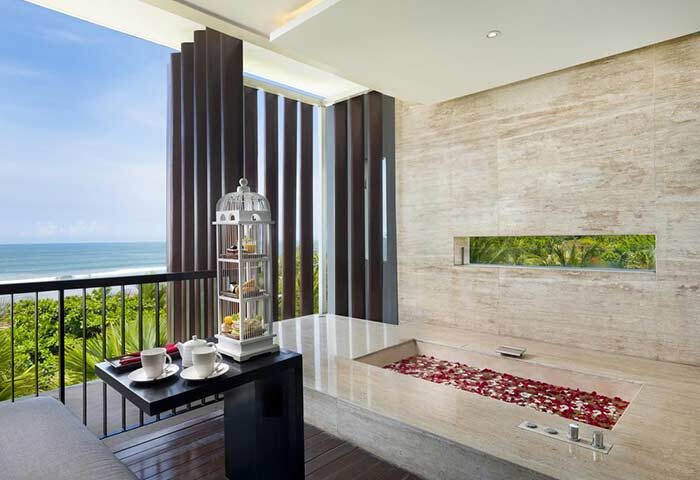 Anantara Seminyak Bali Resort gay-friendly hotel bathroom. Bathtub with rose petals, tea on balcony overlooking the ocean. Luxury travel.