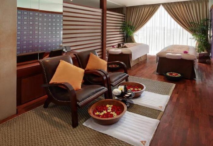 Anantara Seminyak Bali Resort spa. Gay-friendly hotel offers luxury treatments. Foot bath with flowers, massage beds, and relaxation area.