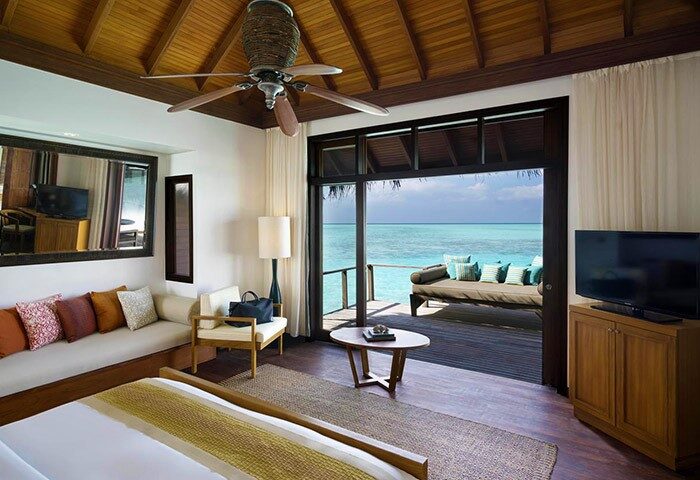 Anantara Veli Maldives Resort's gay-friendly hotel room. Ocean view from overwater bungalow, daybed on deck, ceiling fan, and modern decor.