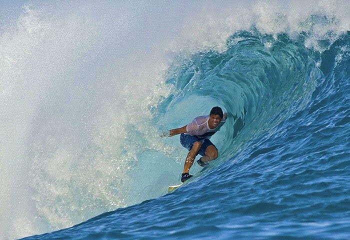 Gay surfer riding a wave at Anantara Veli Maldives Resort. This gay-friendly hotel offers surfing and other water sports activities.