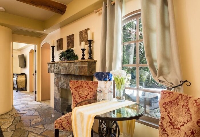 Andalusian Court gay-friendly hotel room with stone fireplace, glass table, and window. A comfortable space for gay men travelers.