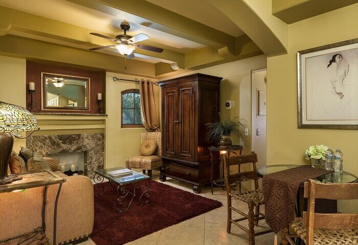 Interior of gay-friendly Andalusian Court hotel. Living space with fireplace, furniture, ceiling fan, and artwork. Gay travel advice.