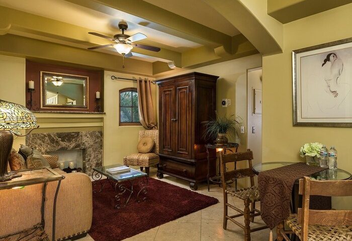 Interior of gay-friendly Andalusian Court hotel. Living space with fireplace, furniture, ceiling fan, and artwork. Gay travel advice.