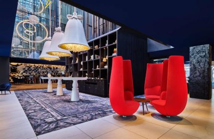 Andaz Amsterdam Prinsengracht lobby with red chairs. Gay-friendly hotel with unique design elements, including bell-shaped chandeliers.