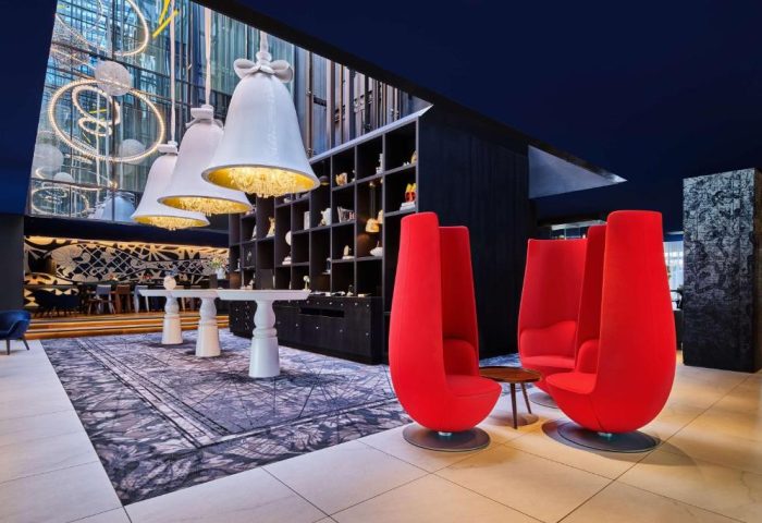 Andaz Amsterdam Prinsengracht lobby with red chairs. Gay-friendly hotel with unique design elements, including bell-shaped chandeliers.