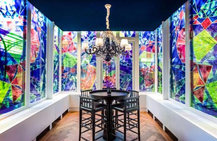 Andaz Amsterdam Prinsengracht gay-friendly hotel: Room with colorful geometric window art, black table and chairs, and chandelier.