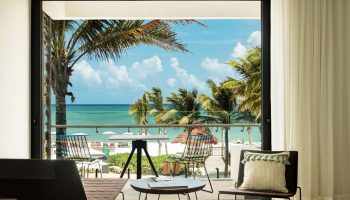 Balcony view at Andaz Mayakoba Resort Riviera Maya, a gay-friendly hotel by Hyatt. Palm trees, beach, and ocean visible. Room's stylish decor.