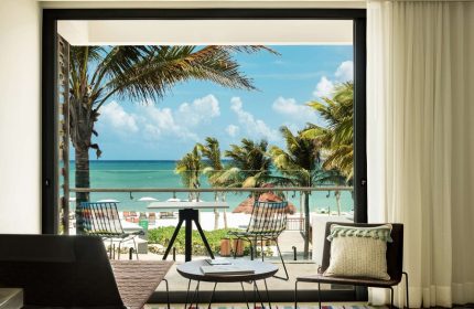 Balcony view at Andaz Mayakoba Resort Riviera Maya, a gay-friendly hotel by Hyatt. Palm trees, beach, and ocean visible. Room's stylish decor.