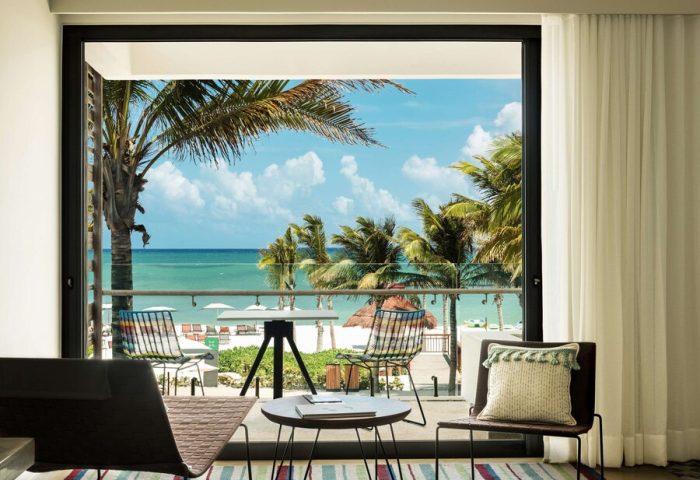 Balcony view at Andaz Mayakoba Resort Riviera Maya, a gay-friendly hotel by Hyatt. Palm trees, beach, and ocean visible. Room's stylish decor.