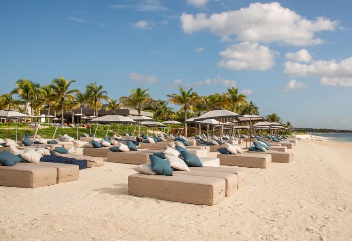 Beachfront at Andaz Mayakoba Resort Riviera Maya, a gay-friendly hotel by Hyatt. Loungers, umbrellas, and palm trees on white sand.