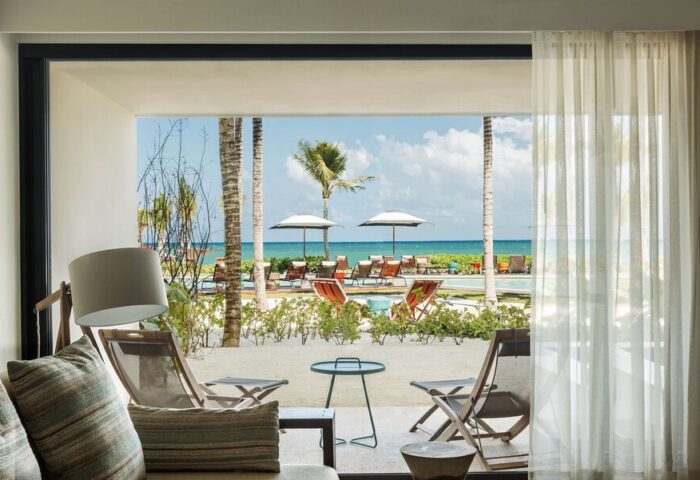 Andaz Mayakoba Resort Riviera Maya, a gay-friendly hotel by Hyatt. Ocean view from a room's patio with beach chairs and palm trees.