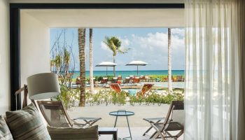 Andaz Mayakoba Resort Riviera Maya, a gay-friendly hotel by Hyatt. Ocean view from a room's patio with beach chairs and palm trees.
