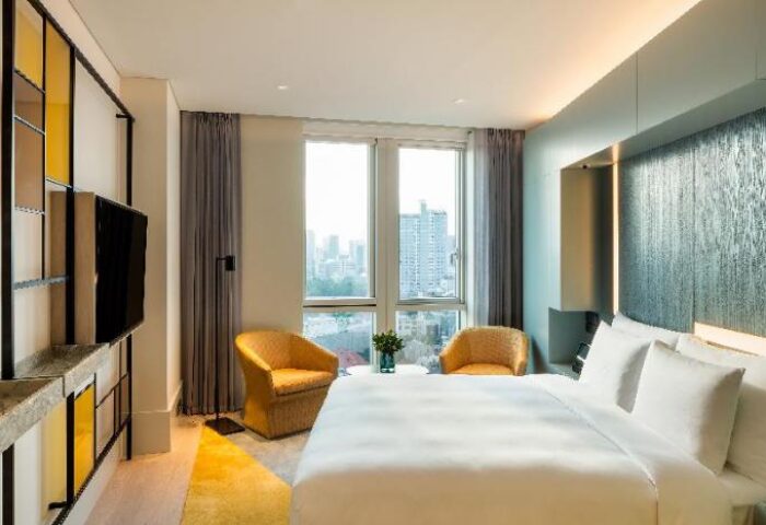 Andaz Seoul Gangnam hotel room. Modern design, king bed, yellow chairs, and city view. Gay-friendly hotel for your Seoul travel adventure.