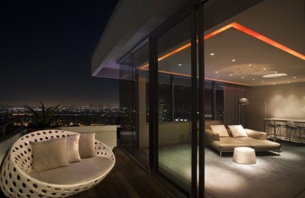 Andaz West Hollywood gay-friendly hotel: Balcony view at night. Modern room with lounge chair, sofa, and city lights. Gay travel luxury.