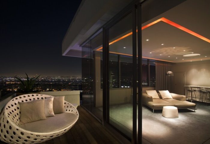 Andaz West Hollywood gay-friendly hotel: Balcony view at night. Modern room with lounge chair, sofa, and city lights. Gay travel luxury.