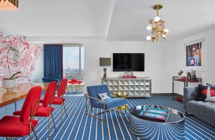Andaz West Hollywood suite. A gay-friendly hotel with colorful decor, red chairs, blue carpet, and city views. Modern design, luxury travel.