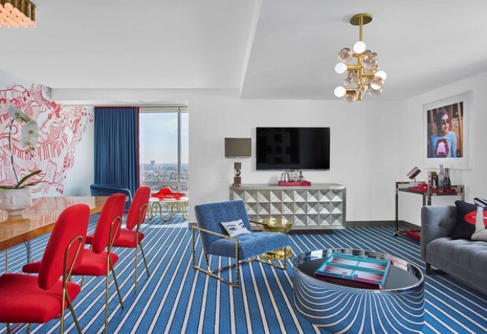 Andaz West Hollywood suite. A gay-friendly hotel with colorful decor, red chairs, blue carpet, and city views. Modern design, luxury travel.
