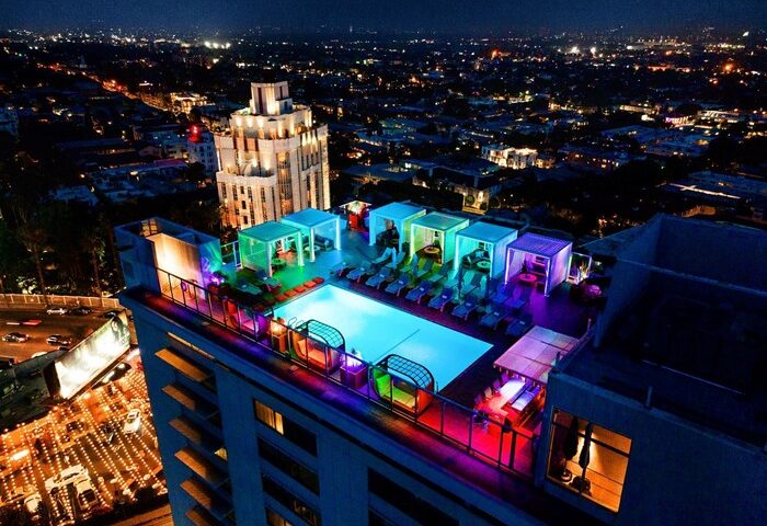 Andaz West Hollywood's rooftop pool at night. A gay-friendly hotel with colorful lights, cabanas, and city views. Perfect for gay travel.