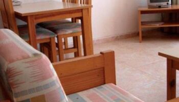 Apartamentos Lido gay-friendly hotel room. Interior of a room with a table, chairs, TV, and couch. Gay travel advice.