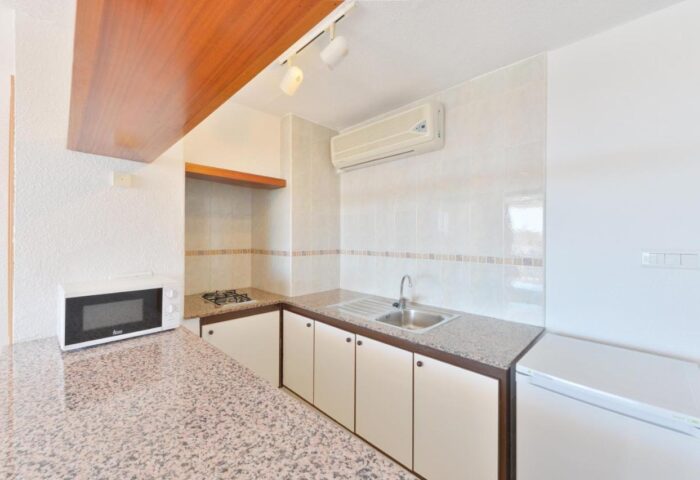 Apartamentos Lido kitchen area. Gay-friendly hotel with microwave, sink, and refrigerator. Ideal for gay men travelers, offering comfort.