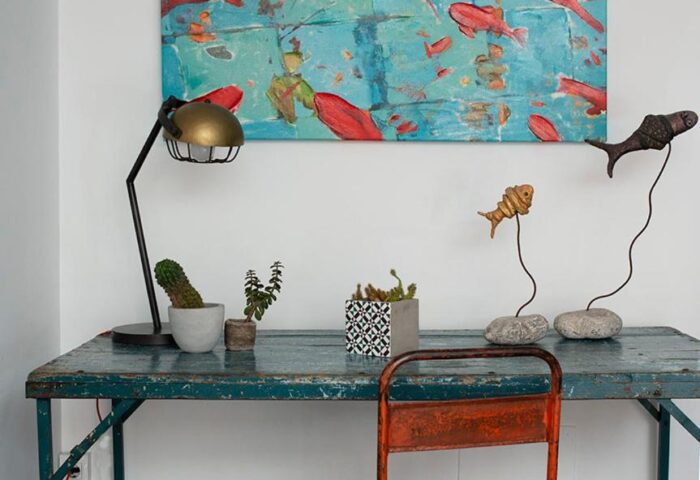 Apartamentos Llobet desk detail. Gay-friendly hotel decor with fish art, lamp, and plants. Rustic charm in this gay travel destination.