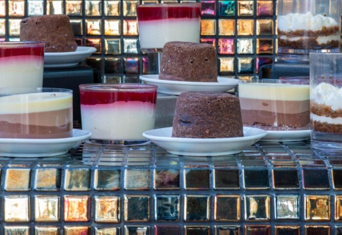 Desserts at Gay-Friendly Hotel Apartamentos Llobet. Puddings and layered desserts on a reflective tiled surface. Delicious treats, gay travel.