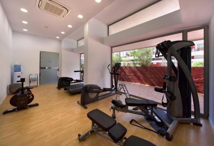 Gym at Gay-Friendly Hotel Apartamentos Llobet. Fitness equipment includes treadmill, elliptical, stationary bike, weight machines, and free weights.