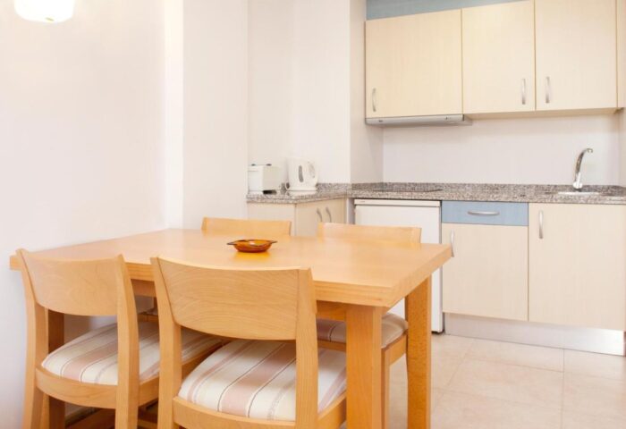 Gay-Friendly Hotel Apartamentos Mar y Playa kitchen area. Dining table with chairs, cabinets, and essential appliances for a comfortable stay.