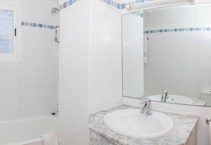 Gay-Friendly Hotel Apartamentos Mar y Playa bathroom. Clean white tiles, sink, mirror, and bathtub. Ideal for gay men travel.