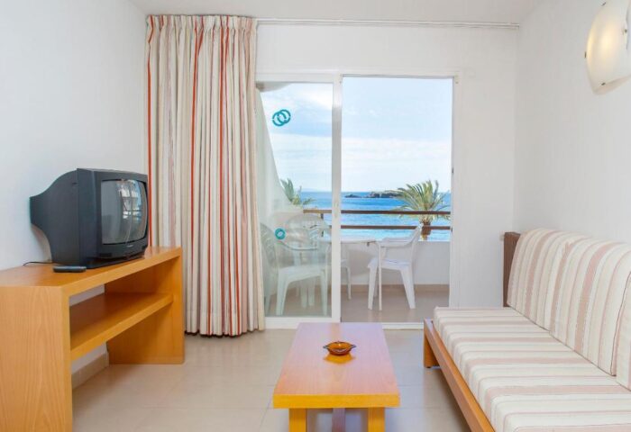 Gay-Friendly Hotel Apartamentos Mar y Playa: Living area with TV, couch, and balcony overlooking the sea. Ideal for gay travel.