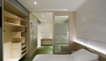 Ako Suites Hotel aparthotel interior. Gay-friendly hotel room with bed, closet, and frosted glass doors. Modern design, sleek and comfortable.