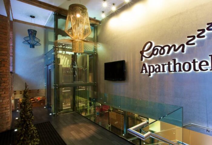 Roomzzz Aparthotel Manchester City lobby. Modern design, glass elevator, stylish lighting. A gay-friendly hotel with unique architecture.