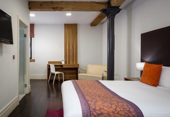 Roomzzz Manchester City aparthotel room. Modern design, desk, sofa, and bed. Gay-friendly hotel in Manchester. Comfortable stay for gay travelers.