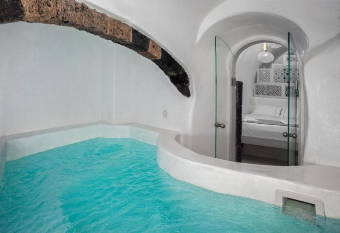 Aperto Suites Adults Only gay-friendly hotel room. Turquoise pool, white walls, glass door to bedroom. Luxury gay travel.