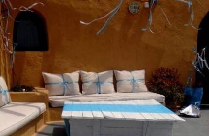 Aperto Suites adults-only gay-friendly hotel patio. Outdoor seating area with pillows and a white table with blue stripes. Relaxing space.
