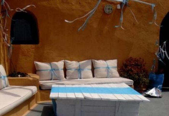 Aperto Suites adults-only gay-friendly hotel patio. Outdoor seating area with pillows and a white table with blue stripes. Relaxing space.