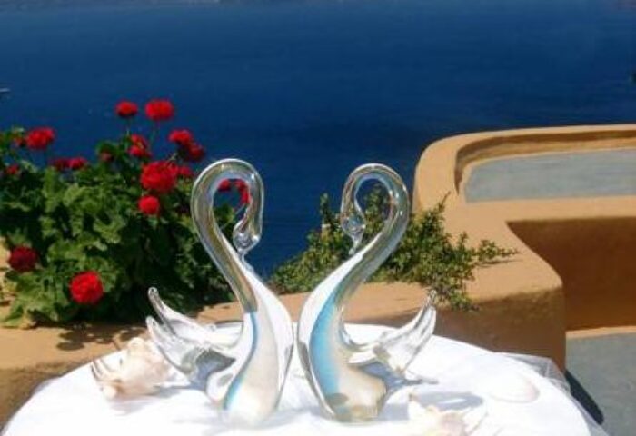 Aperto Suites, an adults-only gay-friendly hotel. Two glass swans on a table with a sea view. Romantic decor for gay couples.