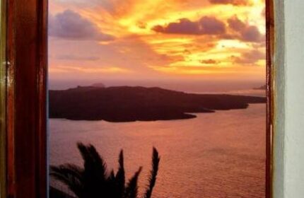View from Aperto Suites, a gay-friendly, adults-only hotel. Sunset over the sea, seen through a window. Palm tree silhouette. Romantic.