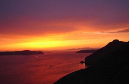 Sunset view from Aperto Suites, an adults-only, gay-friendly hotel. The sky is a mix of purple, orange, and yellow over the sea.