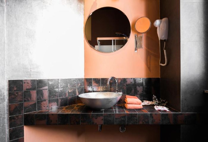 MarcoAurelio49 Apartments' bathroom. Gay-friendly hotel with sink, round mirror, and towels. Stylish design for gay travelers in Rome, Italy.