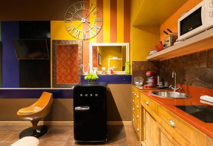 MarcoAurelio49 Apartments gay-friendly hotel kitchen. Colorful design with SMEG fridge, clock, and modern appliances. Rome gay travel.